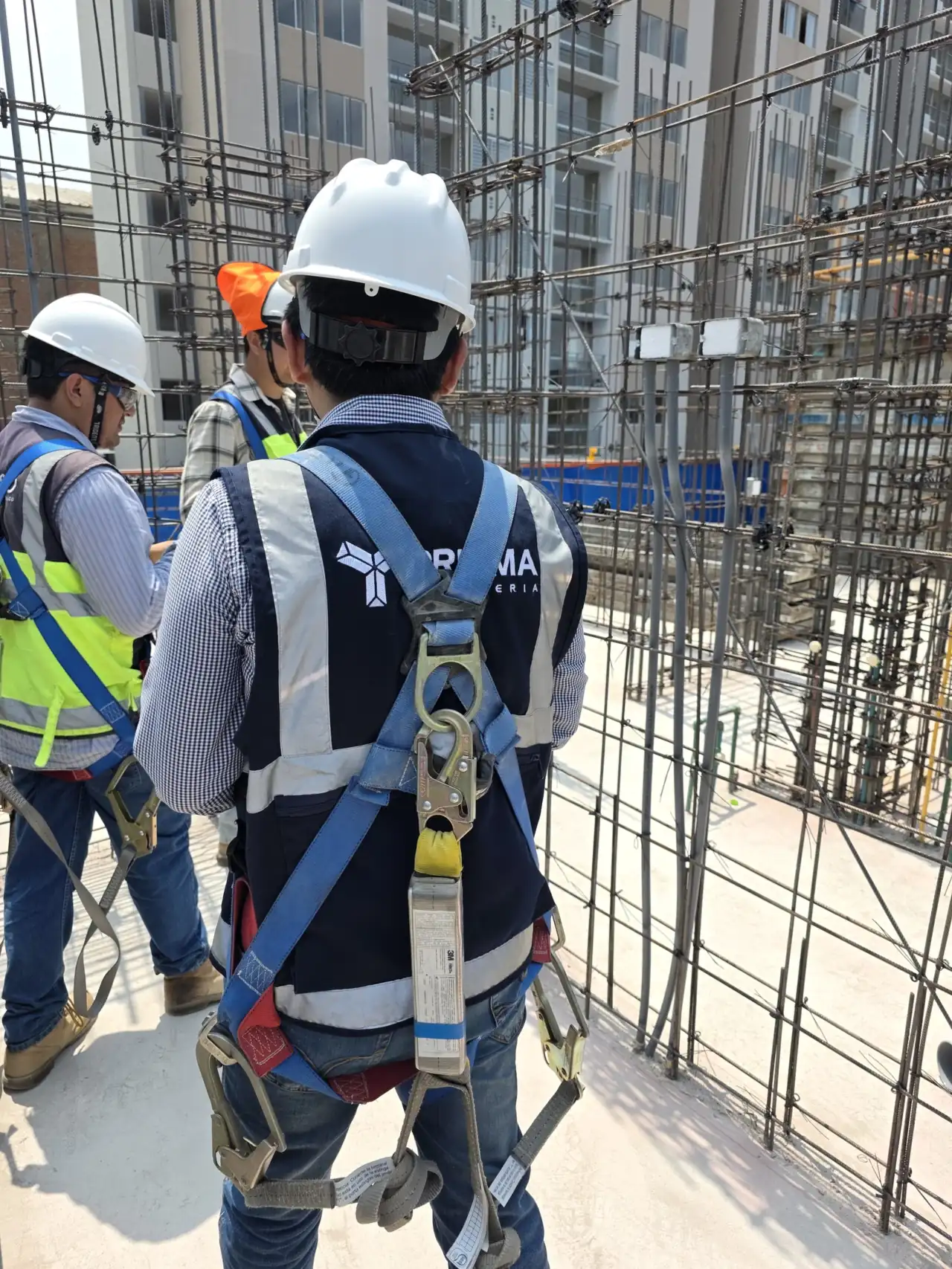 Supervisores de PRISMA con arnés y casco revisando el acero de refuerzo en obra